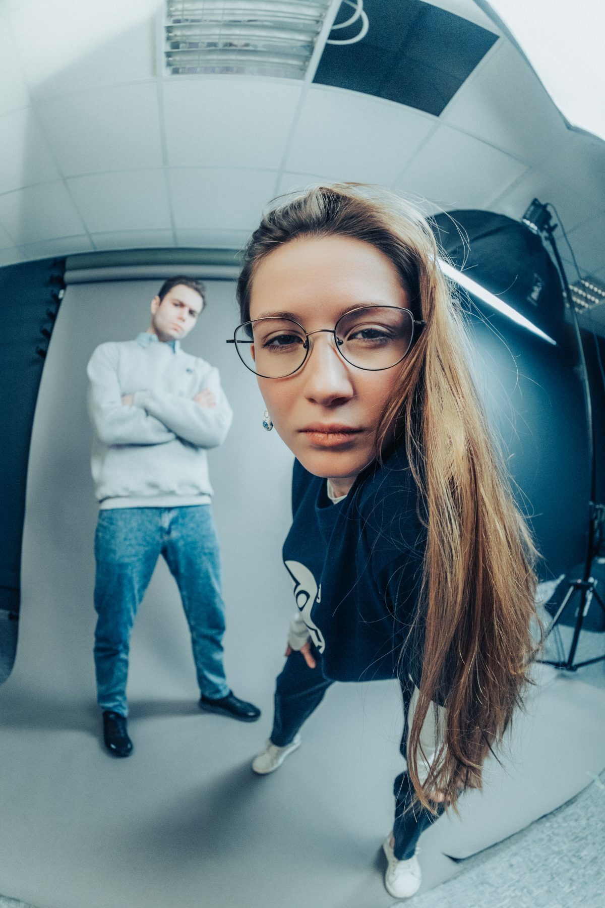 Fisheye studio frame of a model in a printed sweatshirt with a second model behind